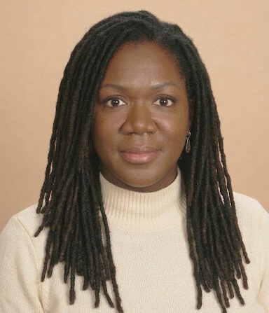 Professional headshot of midwife Adiah smiling confidently in a clinical setting birth center Durham NC